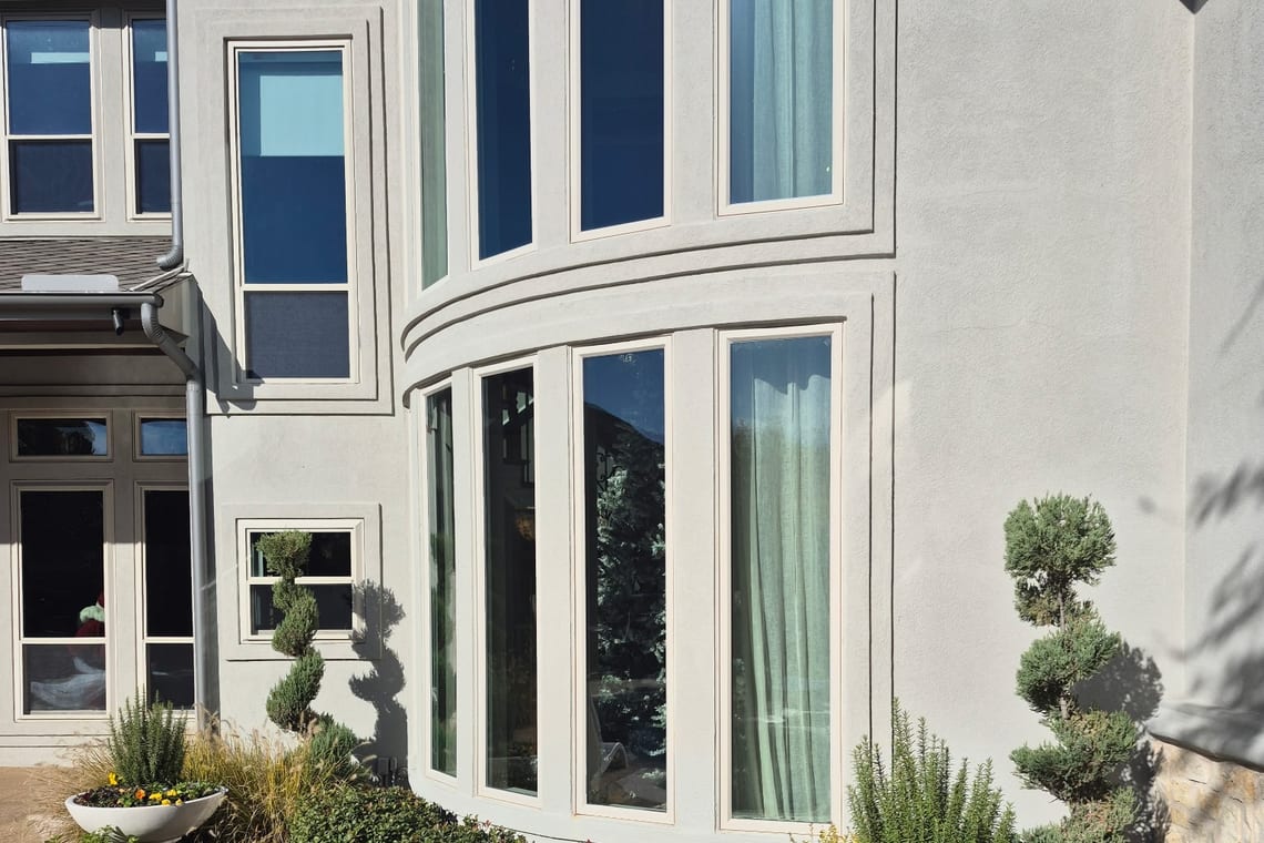 Curved bay windows on a stucco home, the glass clear in full sun